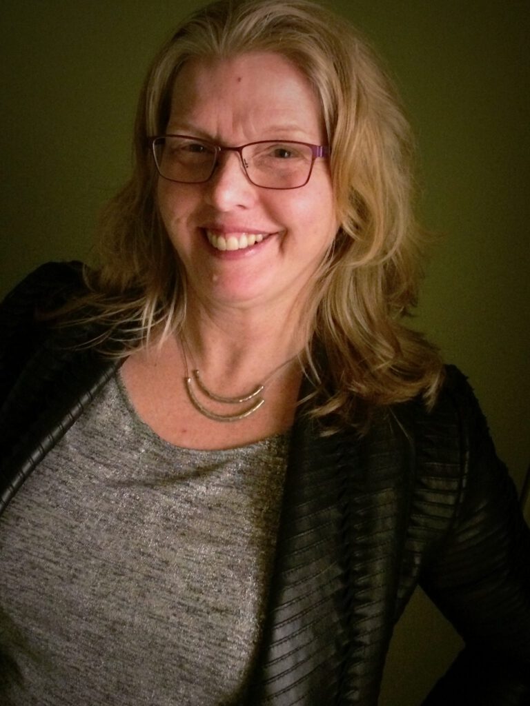 A woman with glasses smiling for the camera.