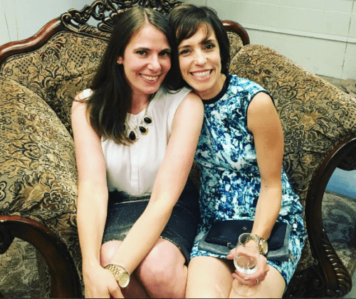 Two women sitting on a chair smiling for the camera.