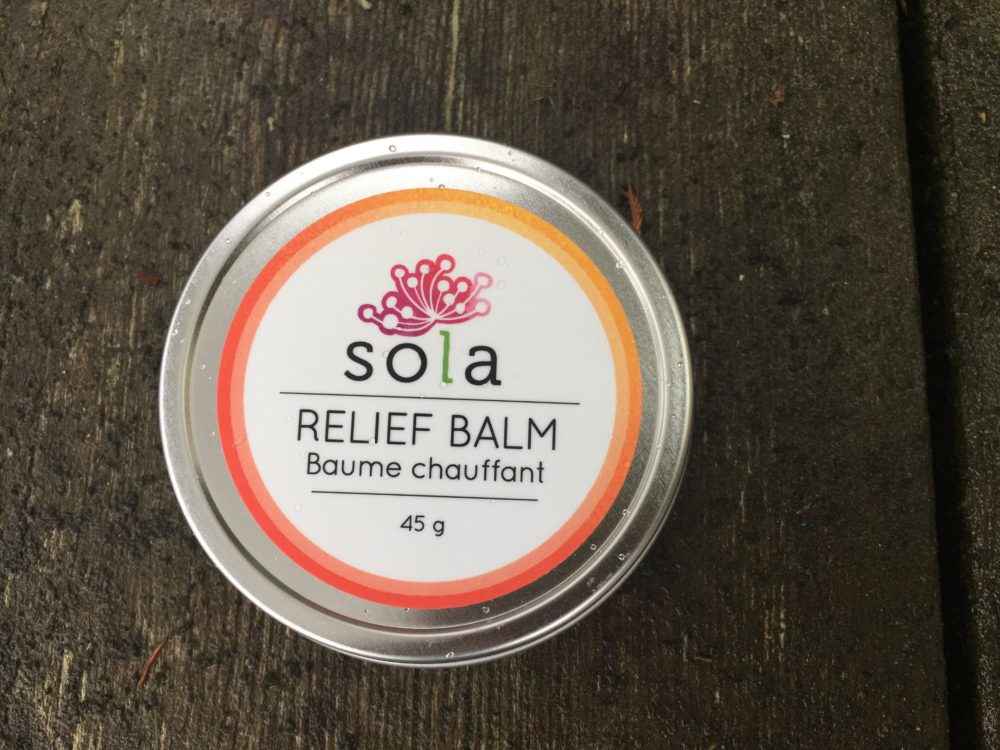 A tin of sola relief balm on top of a wooden table.